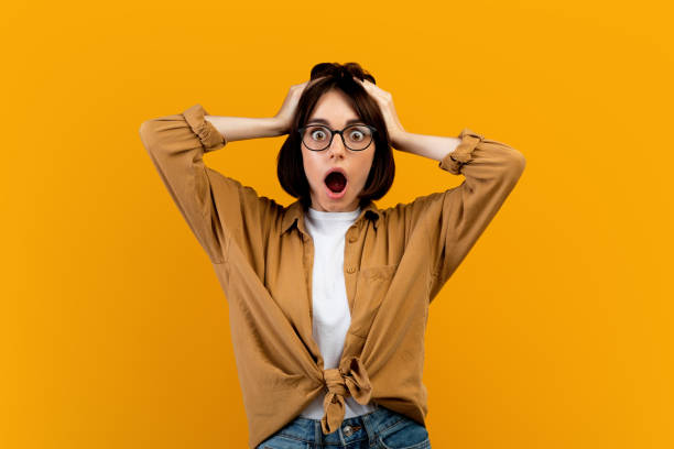 Unbelievable news. Shocked woman touching her head in shock over yellow studio background, cannot believe amazing offer Unbelievable news. Shocked woman touching her head in shock over yellow studio background. Amazed lady cannot believe amazing offer or sale, opening her mouth in surprise wtf stock pictures, royalty-free photos & images