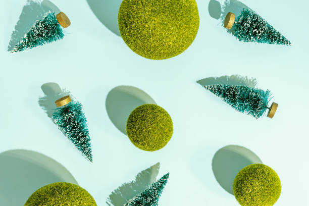 istock Toy christmas trees and green grass balls scattered on blue background. Conceptual pattern with hard shadows 1344027442