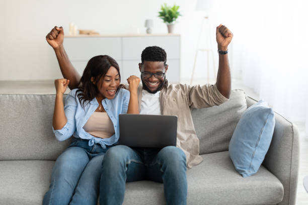 istock African american couple using laptop, celebrating win 1344030657