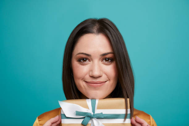 istock A woman holding a gift box under her chin. 1344039548