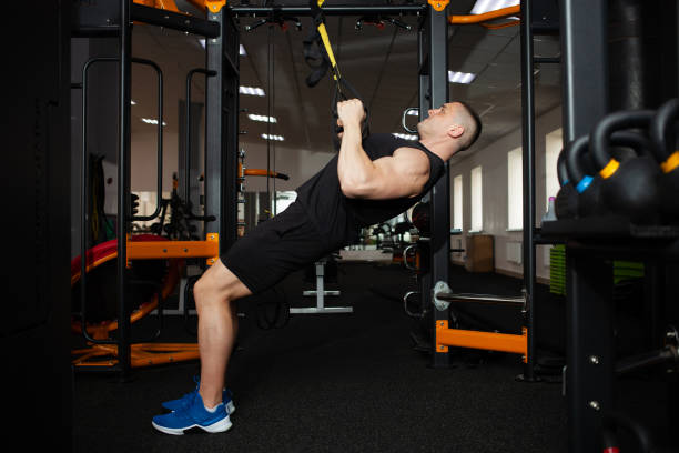 istock A beautiful trainer performs exercises on simulator, squats, push-ups on weight, muscular body. Athlete in the gym, coaching, individual weight loss courses, sports, advertising. 1344039671