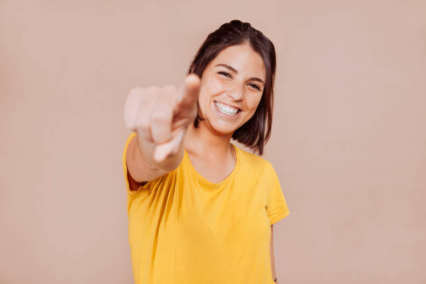 mujer sonriente que te señala con el dedo - young women fotografías e imágenes de stock