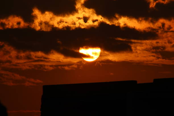 istock sunset view of city  sun going down behind the clouds dark weather 1344041981