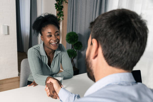 joven empresaria feliz y sonriente estrecha la mano de un empleado a cargo de los recursos humanos de la empresa y es contratada para un nuevo trabajo - opportunity handshake job business fotografías e imágenes de stock