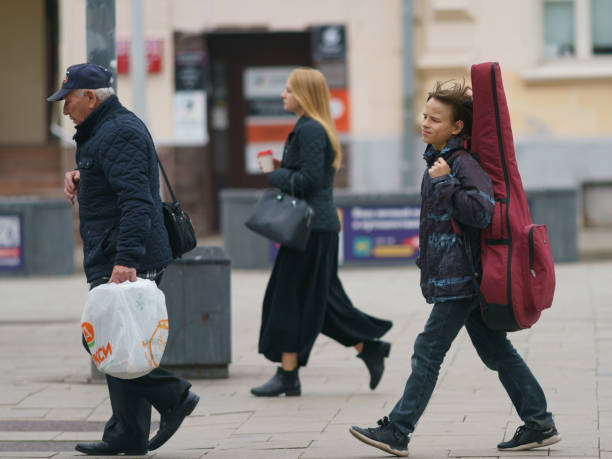 Moscow, Russia - September 27, 2021: People on the city street in the city center. They are serious and purposeful. Schoolboy musician carries guitar in the case like a backpack. Lifestyle concept.