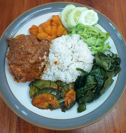 This is steamed white rice with chicken rendang with Terong Balado (eggplant cooked with chilli), Kentang Balado (chopped potatoes cooked in chilli), Tumis Labu or Labu Siam, Daun Singkong (cassava leaves) and raw cucumber.