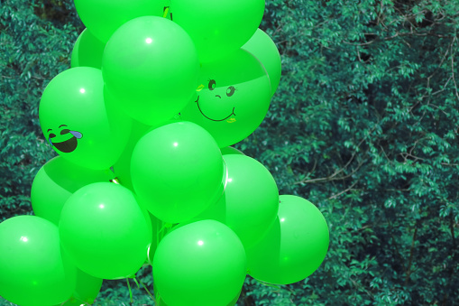 Green balloons in the park for a holiday, place for text