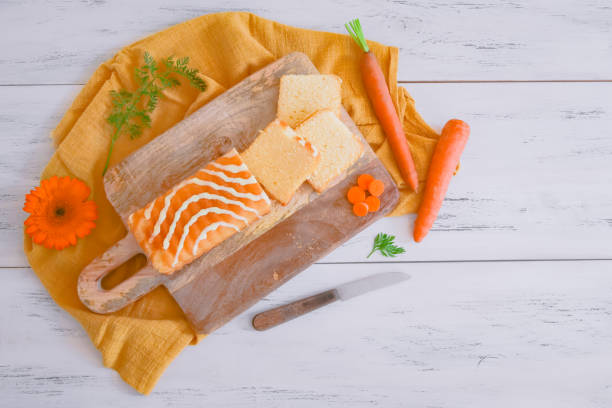 Carrot cupcake on the table A delicious cake with sugar icing, a flower, a knife and a fresh carrot lies on a wooden board on the table, close-up top view. Carrot cake national day concept. carrot cake day stock pictures, royalty-free photos & images