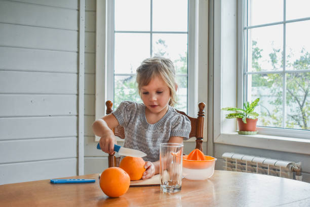 istock child girl in the kitchen cuts and squeezes oranges juice 1344059859