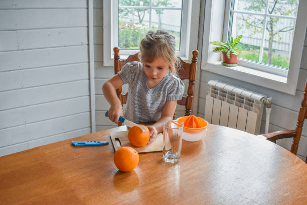 istock child girl in the kitchen cuts and squeezes oranges juice 1344059931