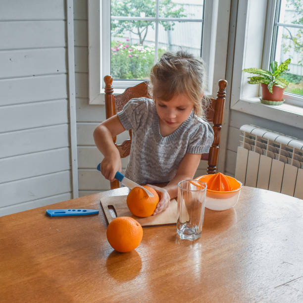 istock child girl in the kitchen cuts and squeezes oranges juice 1344060043