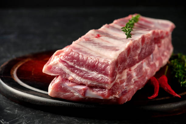 istock Raw pork ribs with spices and thyme on a dark wooden background 1344060164