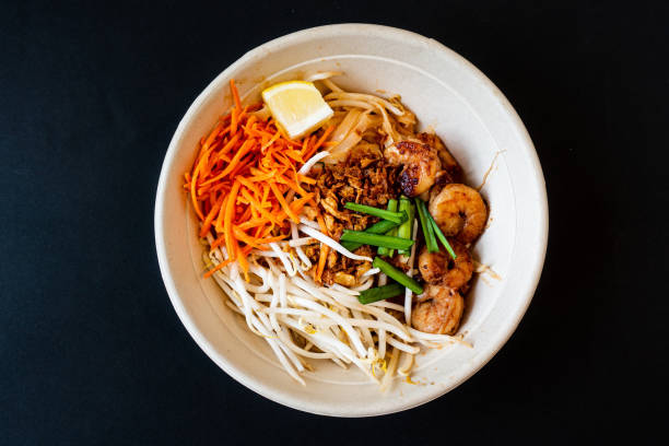 Asian dish Pad Thai prepared with noodles, grilled shrimps, soy sprouts, carrots pieces and sprinkle with peanuts to serve a delicious meal