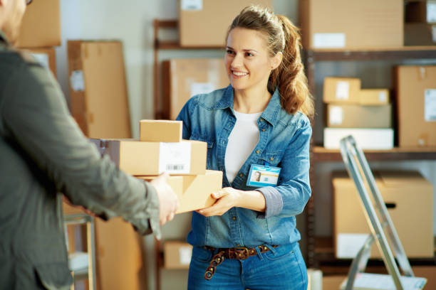 istock smiling young female in jeans in office giving parcel 1344062099