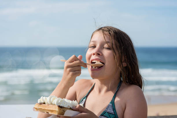 portrait of a pretty little girl enjoying a waffle by the sea