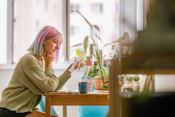 Young woman using laptop while drinking hot drink at home