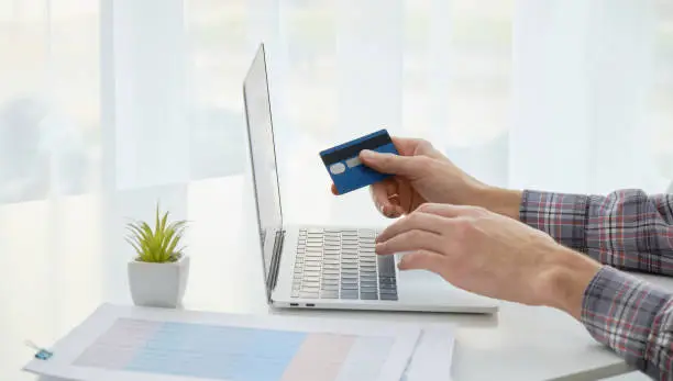 Photo of Hands holding credit card and using laptop. Online shopping