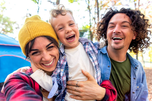 jeune heureux portrait de famille camping en plein air avec tente dans la nature d’automne. maman, papa et petit enfant faisant un selfie pov dans la nature. les gens s’amusent ensemble en s’étreignant en souriant. mode de vie - camping family tent couple photos et images de collection