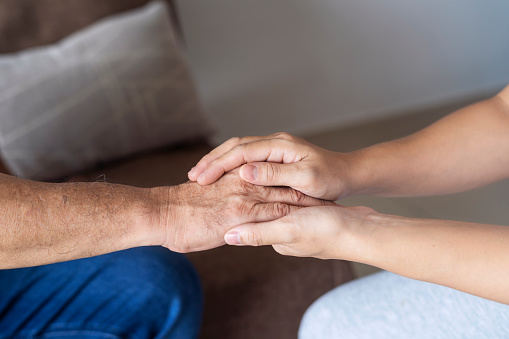 Caregiver, carer hand holding elder hand in hospice care. Philanthropy kindness to disabled concept