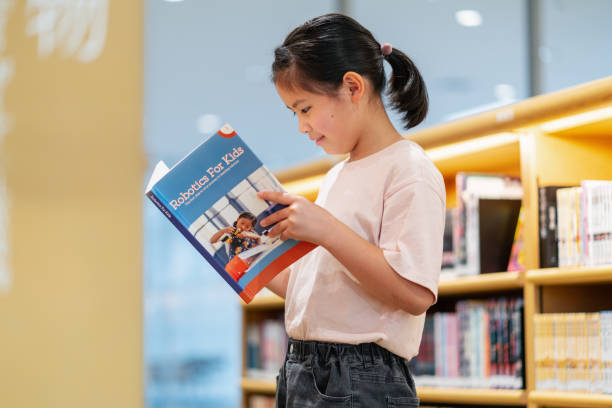 istock Young girl reading a book in a library 1344078832
