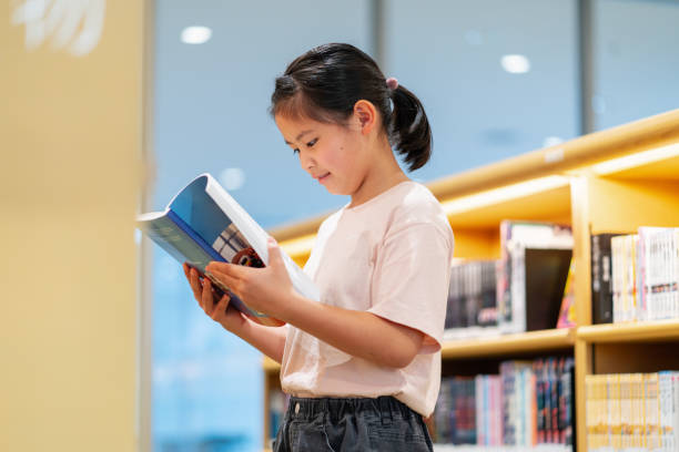 istock Young girl reading a book in a library 1344078880