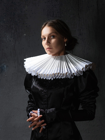 An elegant young lady in an old medieval costume, a portrait in the style of painting. Spanish round collar and dark dress, portrait in the Renaissance style