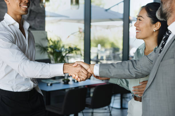 istock Smiling businessmen shaking hands before sitting down at table for meeting 1344081994