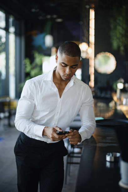 istock Businessman standing by the bar and using his smartphone 1344082088