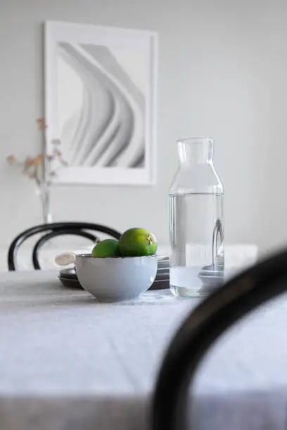 Close up view of a home kitchen table with decor, a carafe, bowl and other kitchen utensils.