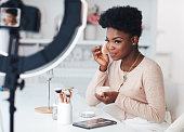 istock happy young african american woman streaming a beauty vlog from home, online content creator applying a makeup on 1344083629