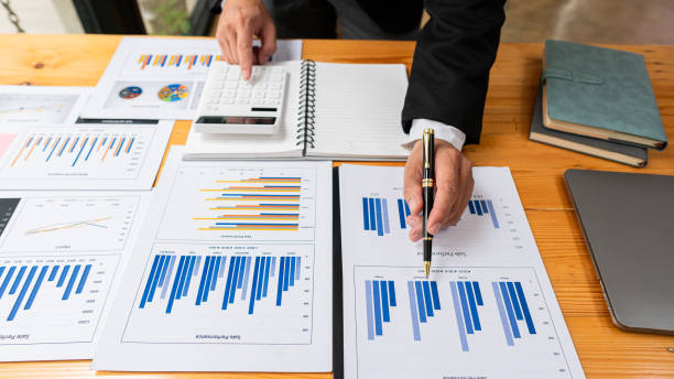 istock top view businessman holding pen to analyze and discuss and brainstorm data chart financial report concept work consulting office An accountant working on a desk using a calculator to calculate finances. 1344084010