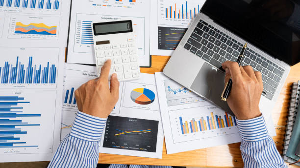 istock top view businessman holding pen to analyze and discuss and brainstorm data chart financial report concept work consulting office An accountant working on a desk using a calculator to calculate finances. 1344084019