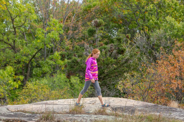 A cute little girl engaged in the sports of rock climbing on the rock, outdoor extreme sport and active lifestyle, natural rock mountains