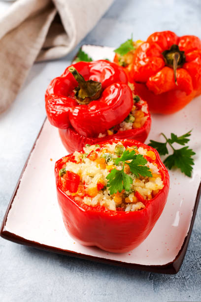 istock Red bell peppers stuffed with rice and vegetables on cast iron pan on gray concret background 1344084581