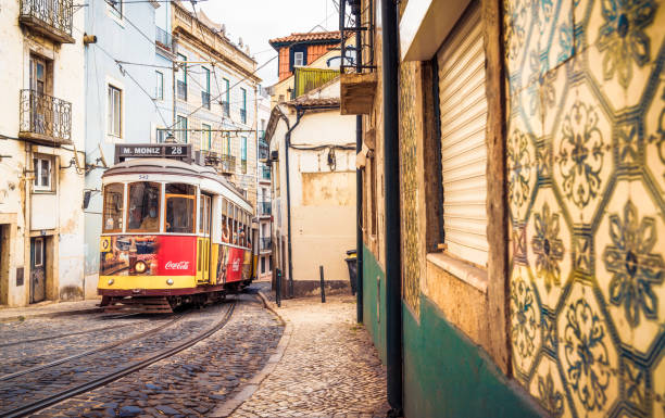 Lisbon, Portugal - Tram 28 climbing one of Lisbon's many hills, passing traditional apartment buildings decorated with tiles.