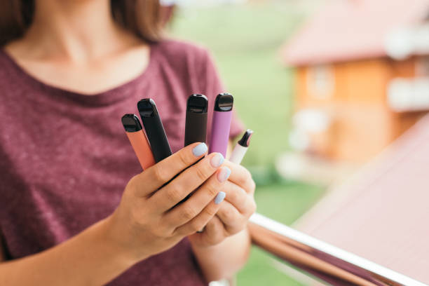 many different disposable e-cigarettes in hand with delicious tastes - disposable imagens e fotografias de stock