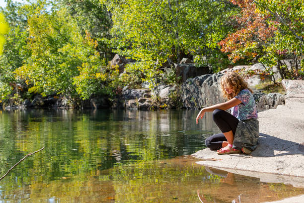 istock Girl Sitting Next to Old Granite Quarry Pond 1344091203