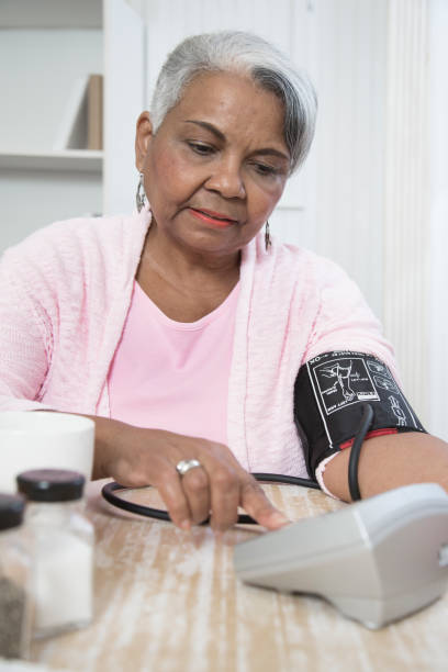Lovely Senior African American woman monitors her blood pressure. stock photo