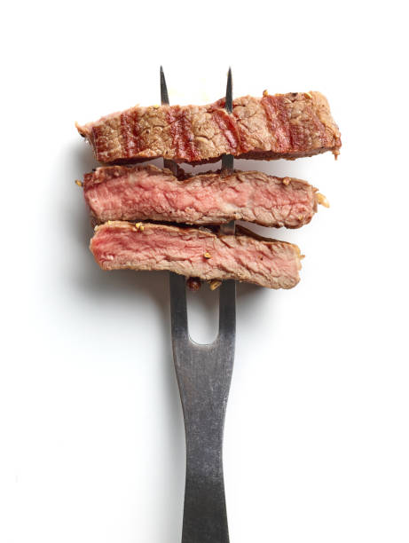 istock Slices of beef steak on meat fork isolated on white from above 1344094189