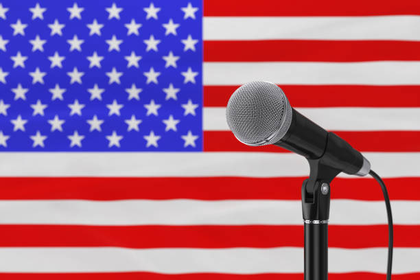 istock Speech Microphone Stand Against of Blurred USA Flag. 3d Rendering 1344095888