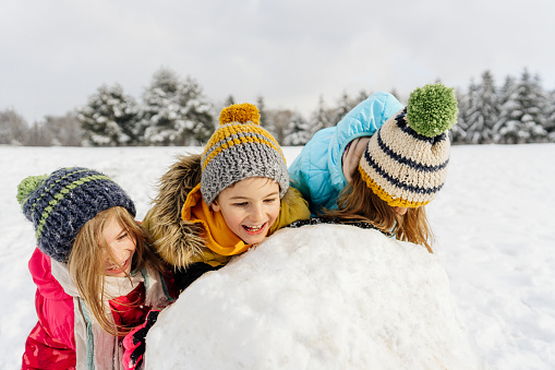 Photo of kids having fun outdoors on a winter day, building a snowman