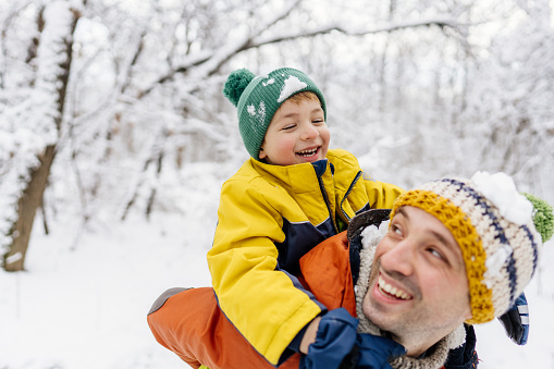 Photo of father and son enjoying together in the snowy forest