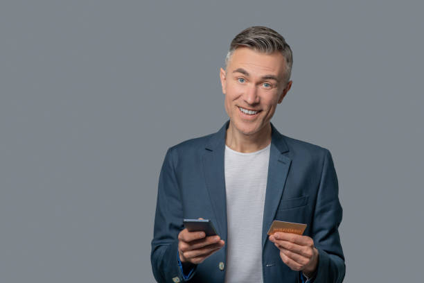 istock Optimistic successful man with smartphone and credit card 1344100602