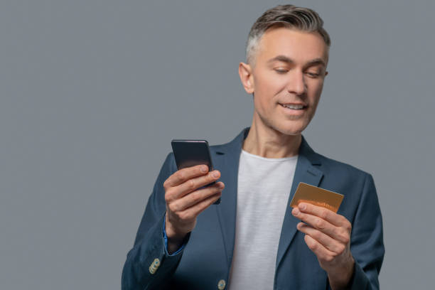 istock Joyful man looking at credit card 1344100612