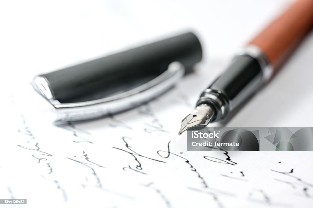 Nostalgic fountain pen and cap on an illegible handwritten letter or manuscript, close-up with selected focus Nostalgic fountain pen and cap on an illegible handwritten letter or manuscript, close-up with selected focus and narrow depth of field Fountain Pen Stock Photo