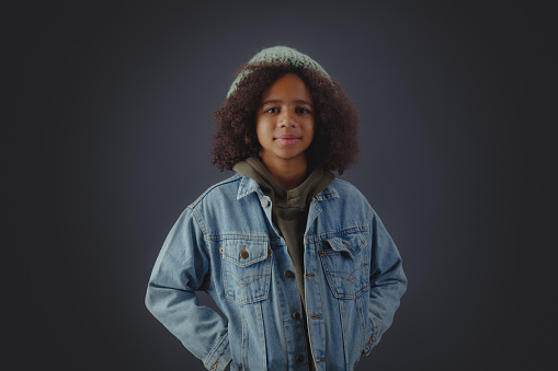 Lovely stylish teenage girl in denim jacket against dark background