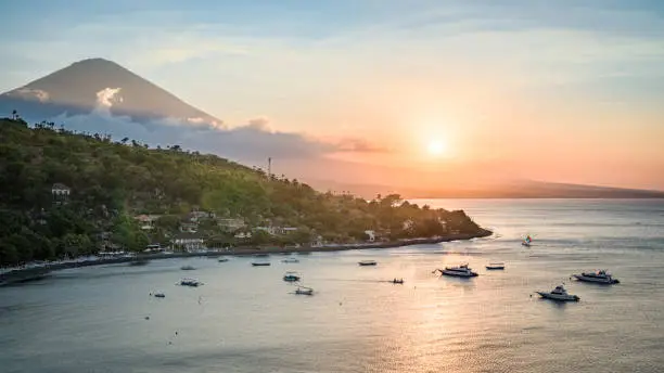 Landscape of Bali north coastline at sunrise, with Mount Agung volcano peak and forest slopes, and Java sea, from hilltop near Amed, Bali, Indonesia