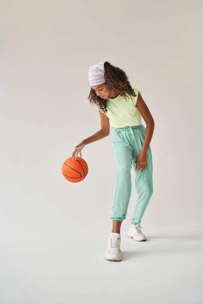 petite fille noire jouant au basket en studio - dribbler sports photos et images de collection