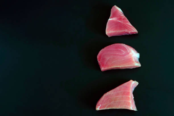surowy stek z tuńczyka na czarnym tle. koncepcja zdrowej diety, źródła białka, składników do gotowania, przydatnych pierwiastków śladowych, witamin i kwasów omega. miejsce na kopiowanie. - tuna steak tuna prepared ahi meat zdjęcia i obrazy z banku zdjęć