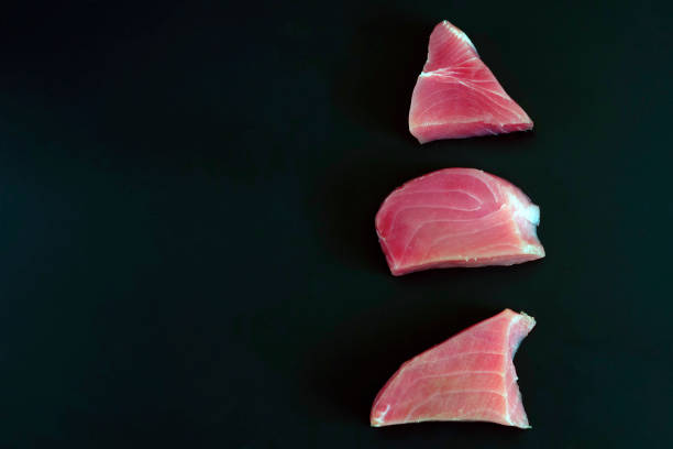 raw tuna steak on a black background. the concept of a healthy diet, a source of protein, ingredients for cooking, useful trace elements, vitamins and omega. copy space. - tuna steak tuna prepared ahi meat imagens e fotografias de stock